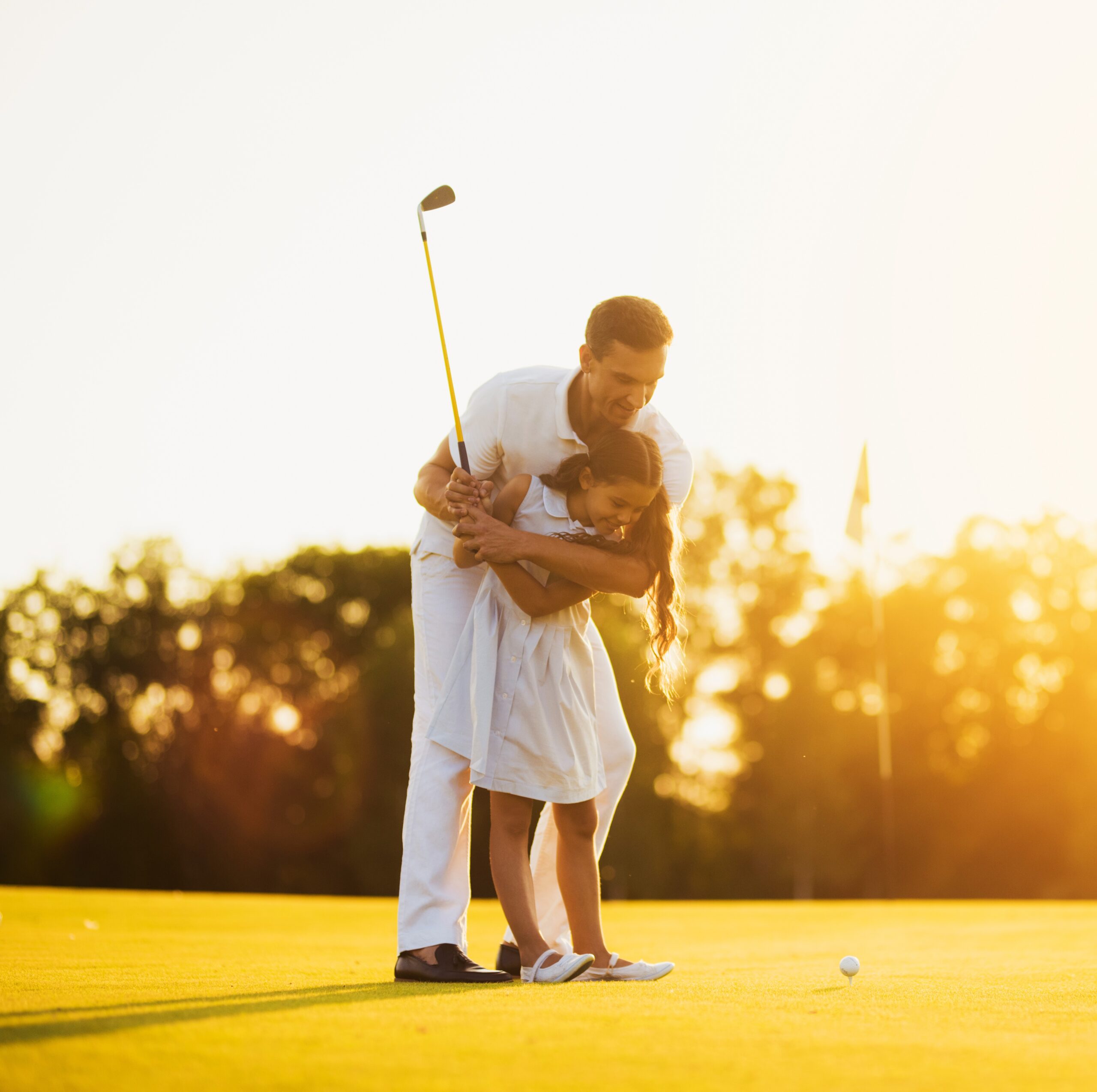 Father teaching his daughter to play golf