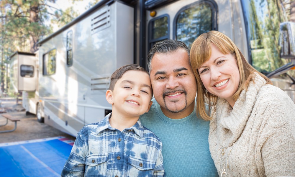 smiling family in front of their RV